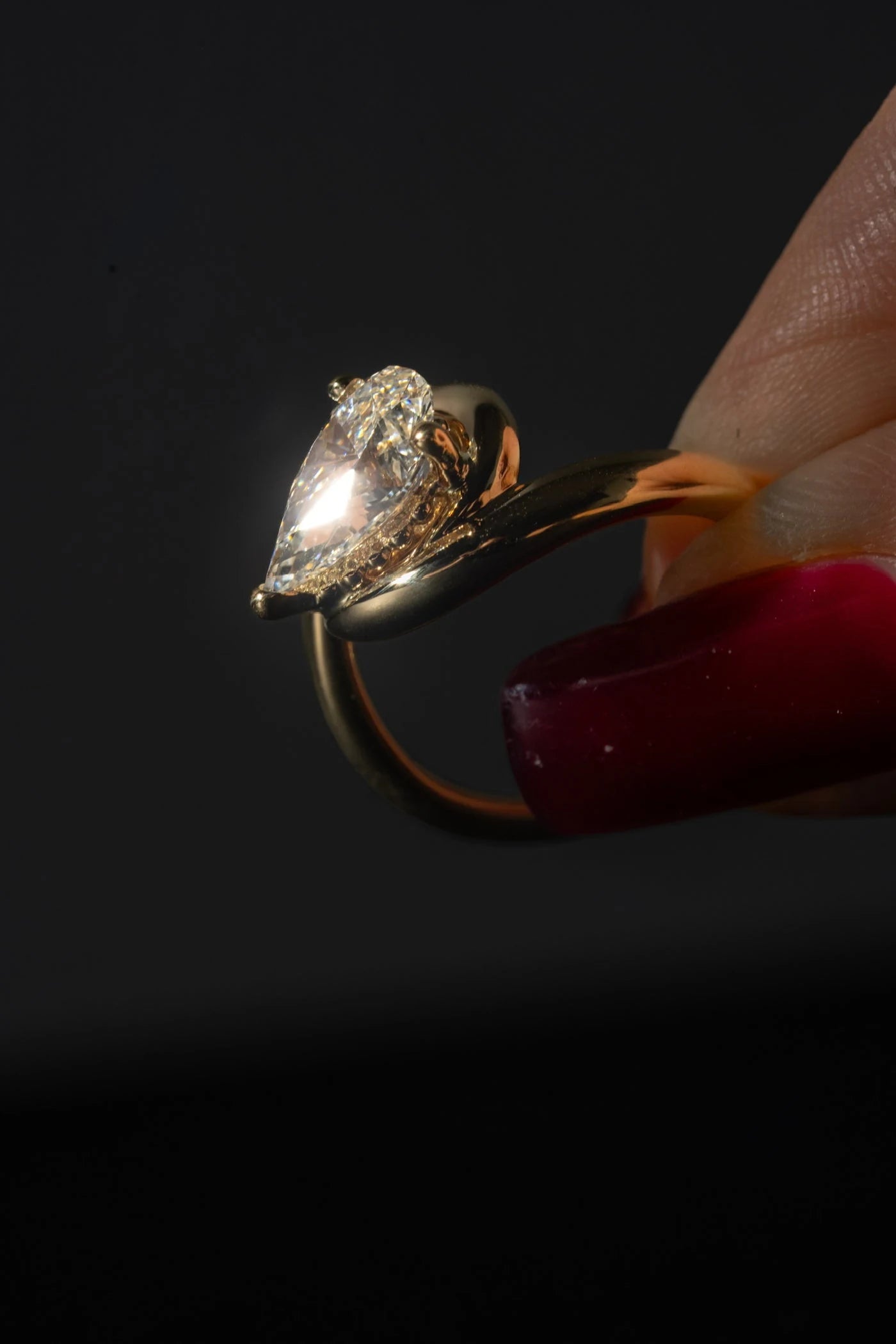 Close view of a ring with a large clear center stone held between fingers