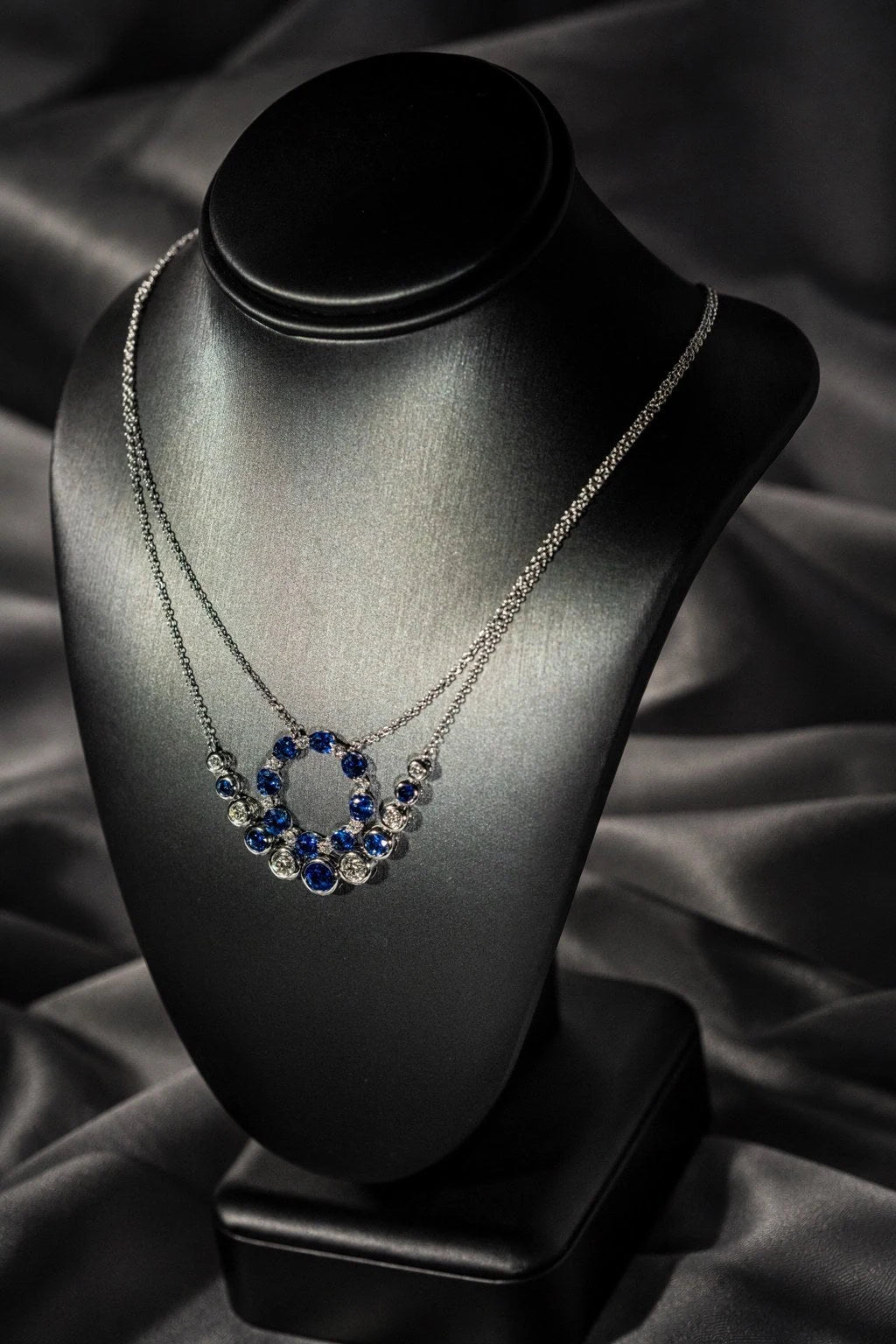 Blue gemstone pendant on a dark necklace display