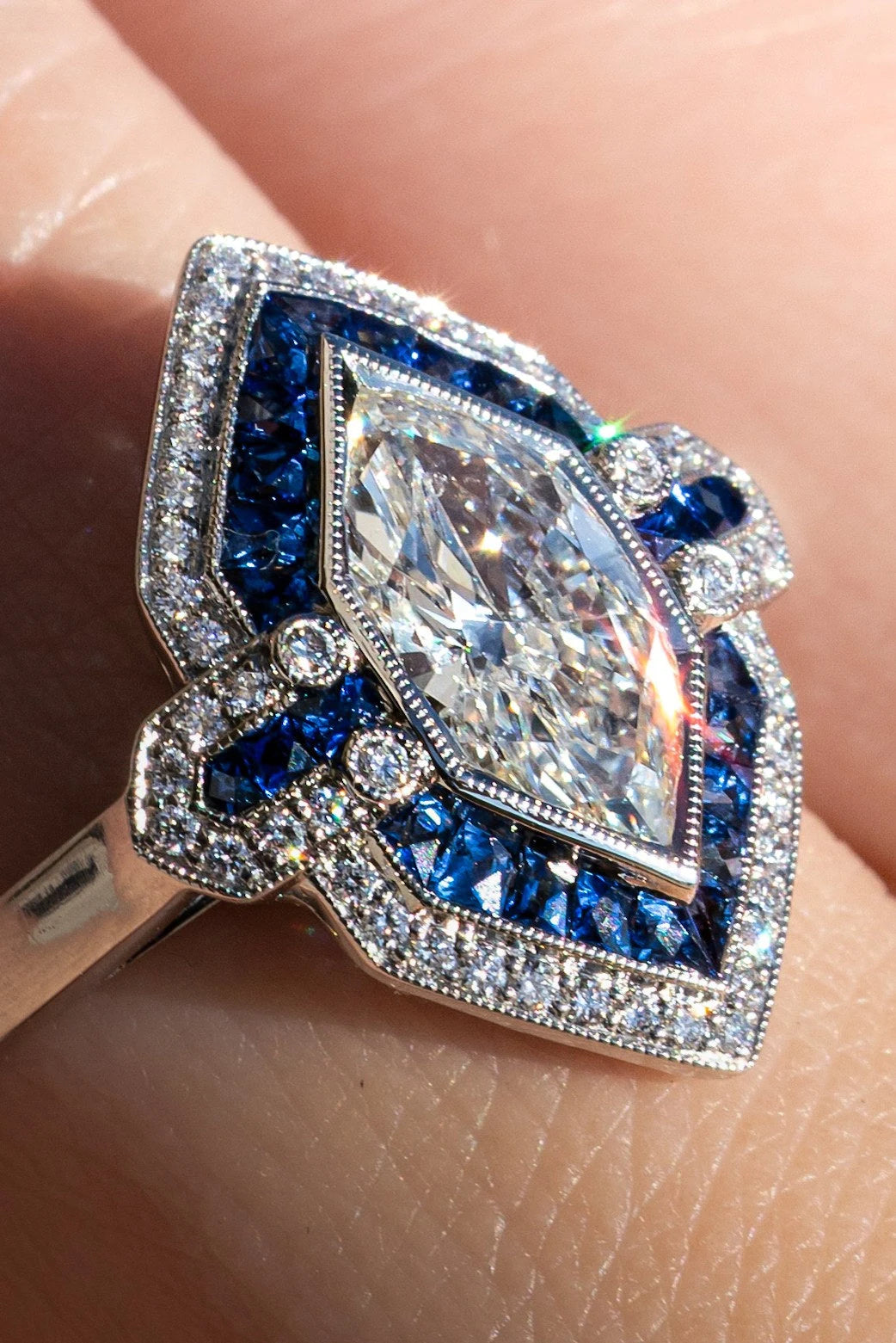 Marquise clear center stone framed by blue gemstones in a ring