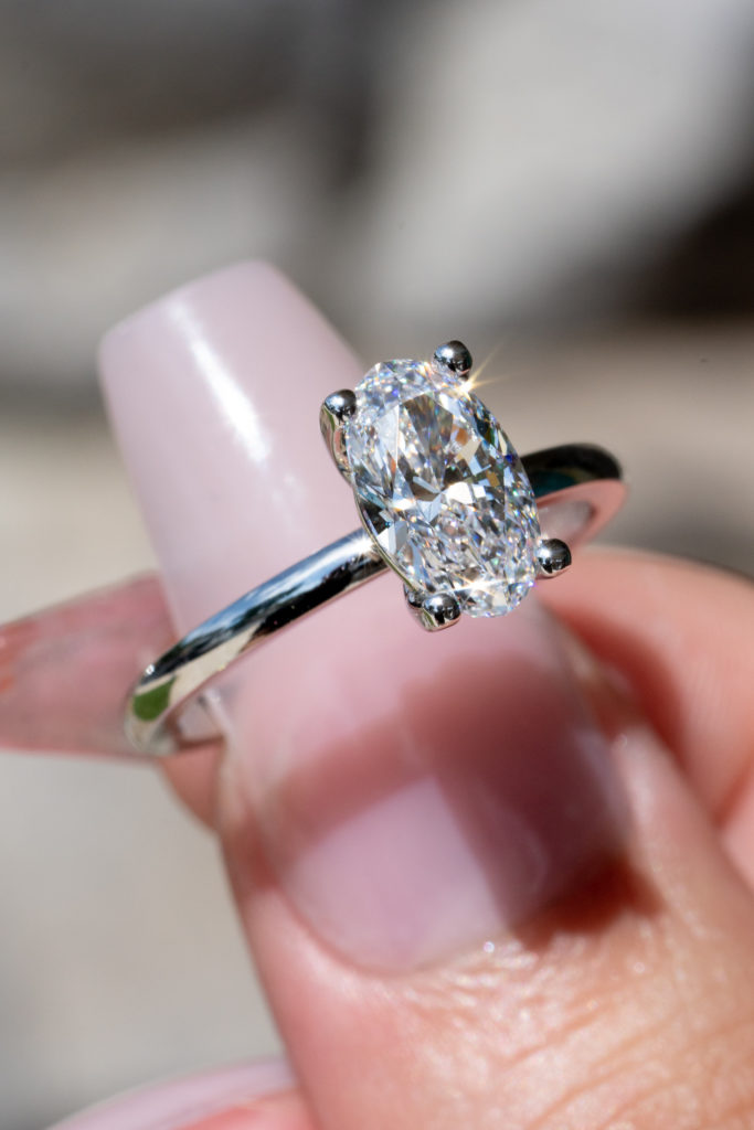 an oval engagement ring with a prong setting on our model's finger
